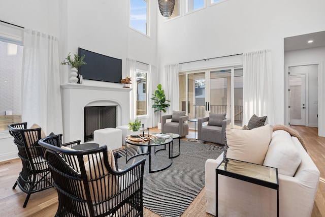 living room with light wood-type flooring, a high ceiling, and a wealth of natural light