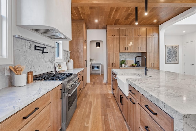 kitchen with wood ceiling, high end range, sink, and backsplash