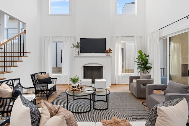 living room with a high ceiling, plenty of natural light, and light hardwood / wood-style floors