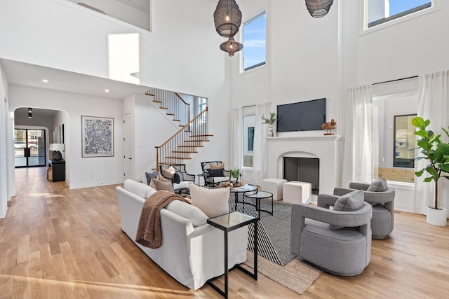 living room with light hardwood / wood-style floors, a healthy amount of sunlight, and a high ceiling