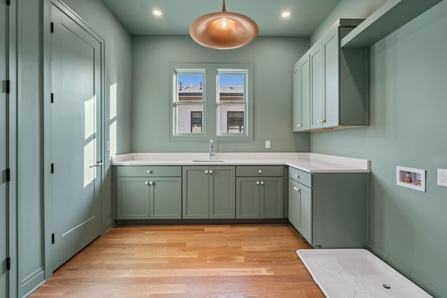 laundry room featuring sink, hookup for a washing machine, light hardwood / wood-style flooring, and cabinets