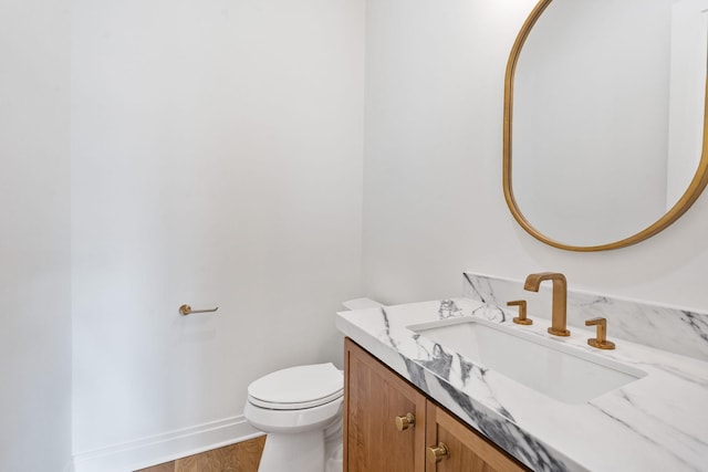 bathroom with hardwood / wood-style flooring, vanity, and toilet