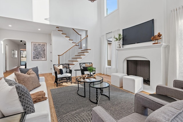 living room with a towering ceiling and light wood-type flooring