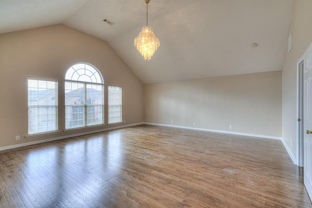 unfurnished room with lofted ceiling, hardwood / wood-style floors, and an inviting chandelier