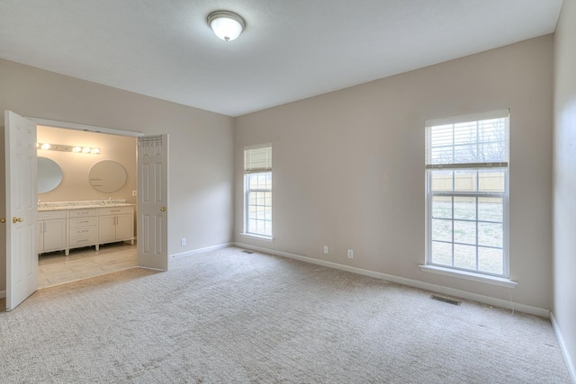 unfurnished bedroom featuring light carpet and connected bathroom