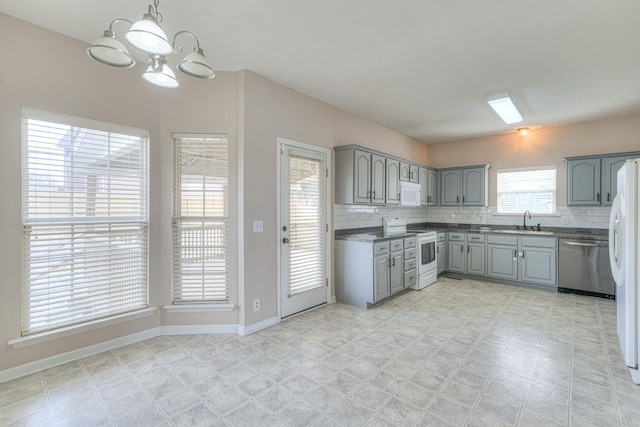 kitchen with pendant lighting, sink, gray cabinetry, decorative backsplash, and white appliances