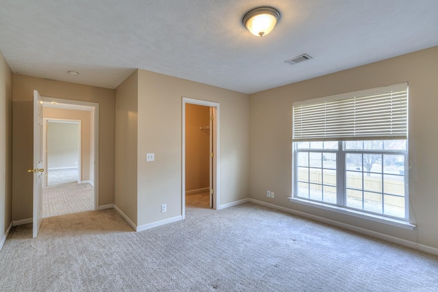 unfurnished bedroom featuring a spacious closet, light colored carpet, and a closet