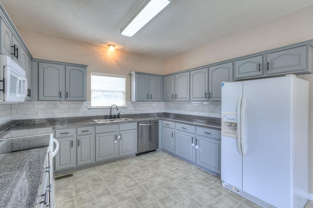 kitchen featuring tasteful backsplash, sink, white appliances, and dark stone counters