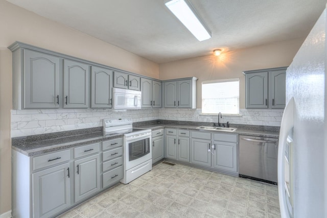 kitchen featuring tasteful backsplash, white appliances, gray cabinets, and sink