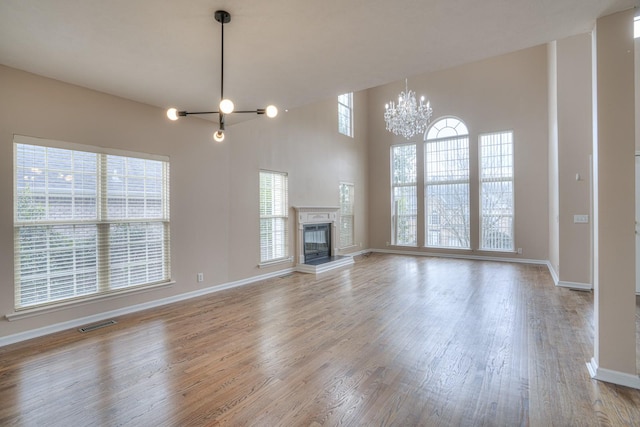 unfurnished living room with an inviting chandelier and light hardwood / wood-style flooring