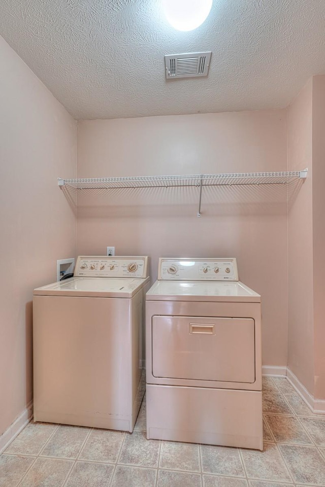 laundry room featuring washing machine and clothes dryer and a textured ceiling