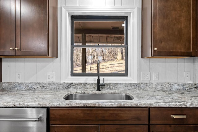 kitchen with dark brown cabinets, sink, stainless steel dishwasher, and light stone counters