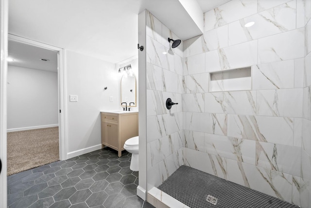 bathroom featuring vanity, a tile shower, and toilet