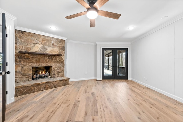 unfurnished living room featuring a fireplace, ornamental molding, light hardwood / wood-style floors, ceiling fan, and french doors