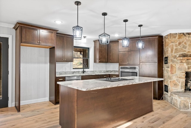 kitchen with pendant lighting, a center island, stainless steel appliances, crown molding, and light hardwood / wood-style flooring
