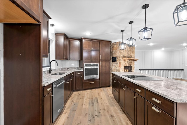 kitchen featuring appliances with stainless steel finishes, sink, hanging light fixtures, light hardwood / wood-style floors, and dark brown cabinets