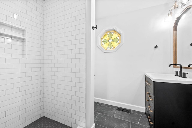 bathroom with vanity and a tile shower