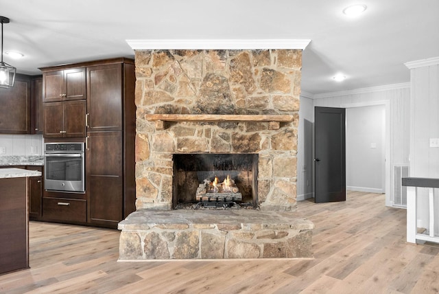 unfurnished living room with ornamental molding, a fireplace, and light hardwood / wood-style flooring