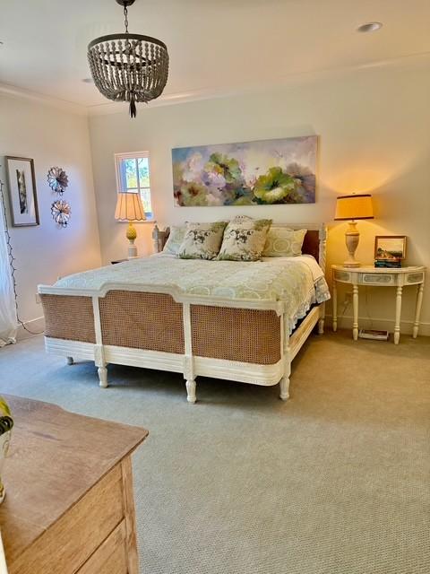 carpeted bedroom with ornamental molding and a chandelier