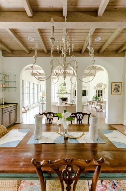 dining area with beam ceiling, an inviting chandelier, and wooden ceiling