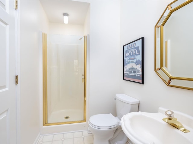 bathroom featuring sink, a shower with shower door, and toilet