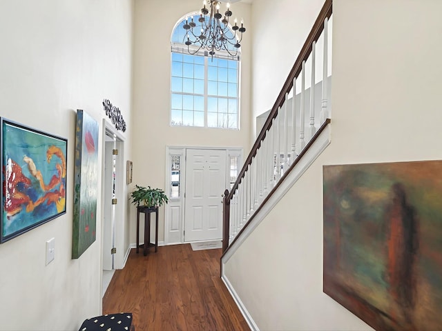 foyer featuring dark wood-type flooring, a towering ceiling, and an inviting chandelier