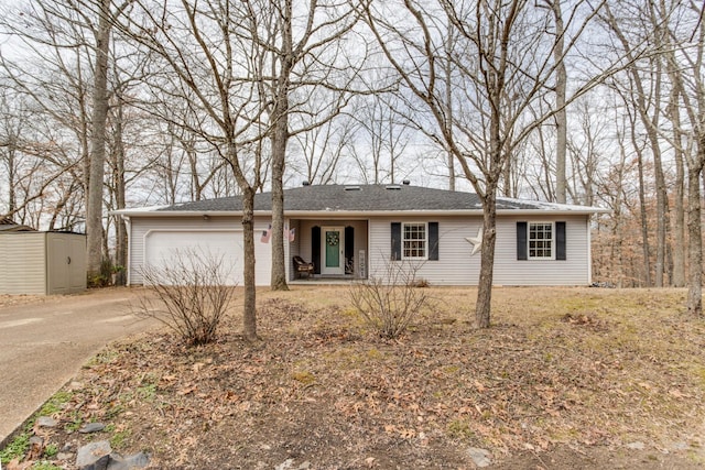 single story home featuring a shed, an attached garage, concrete driveway, and an outdoor structure