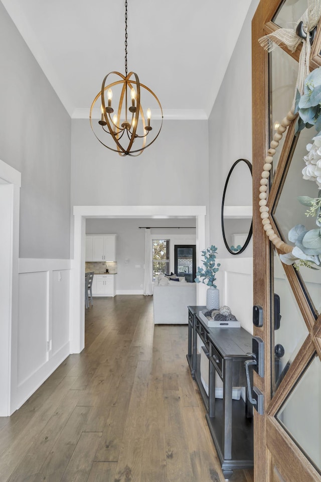 foyer entrance with an inviting chandelier, ornamental molding, and dark hardwood / wood-style flooring