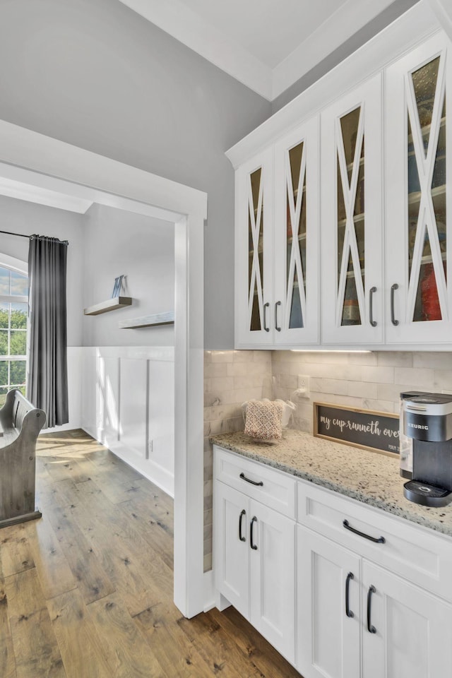 kitchen with hardwood / wood-style flooring, white cabinets, light stone counters, and decorative backsplash