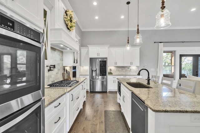 kitchen featuring sink, backsplash, appliances with stainless steel finishes, a kitchen island with sink, and white cabinets