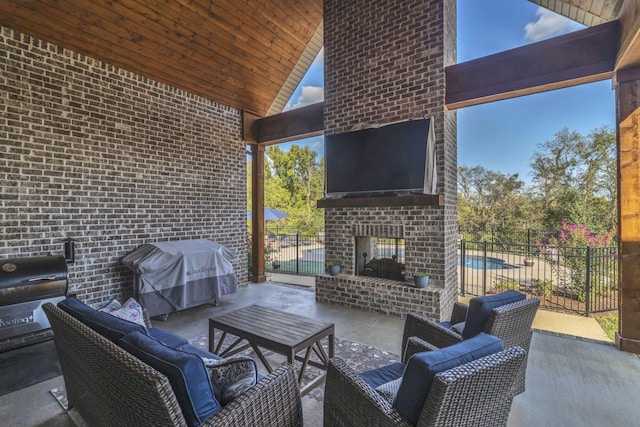 view of patio with an outdoor brick fireplace and a grill