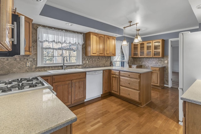 kitchen featuring sink, crown molding, pendant lighting, white appliances, and light hardwood / wood-style floors