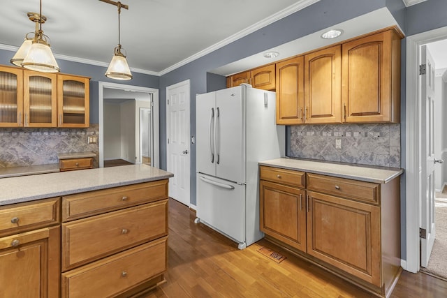 kitchen featuring tasteful backsplash, hanging light fixtures, hardwood / wood-style flooring, and white refrigerator