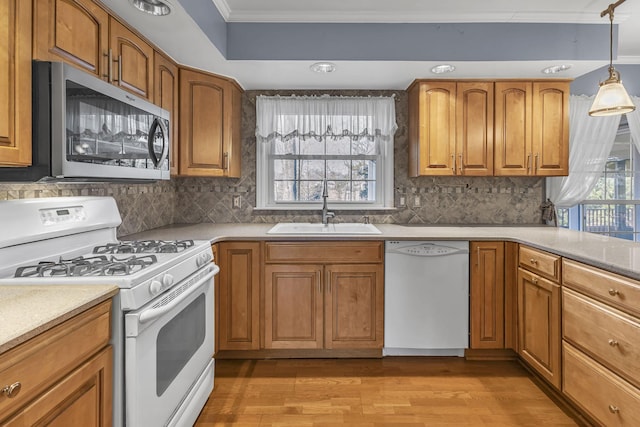 kitchen with sink, crown molding, white appliances, decorative backsplash, and decorative light fixtures