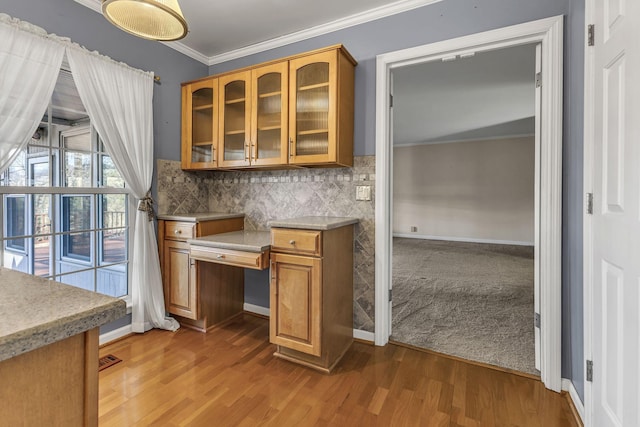 kitchen featuring ornamental molding, carpet flooring, built in desk, and decorative backsplash