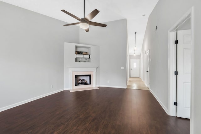 unfurnished living room with ceiling fan, dark hardwood / wood-style floors, and high vaulted ceiling