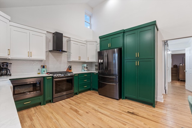 kitchen with white cabinetry, high vaulted ceiling, green cabinets, stainless steel appliances, and wall chimney range hood