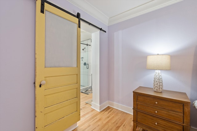 hallway with crown molding, a barn door, and light wood-type flooring