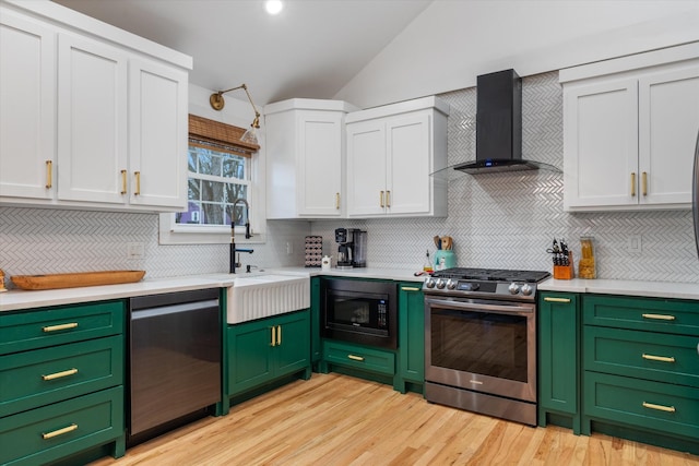 kitchen with built in microwave, dishwasher, lofted ceiling, gas stove, and wall chimney range hood