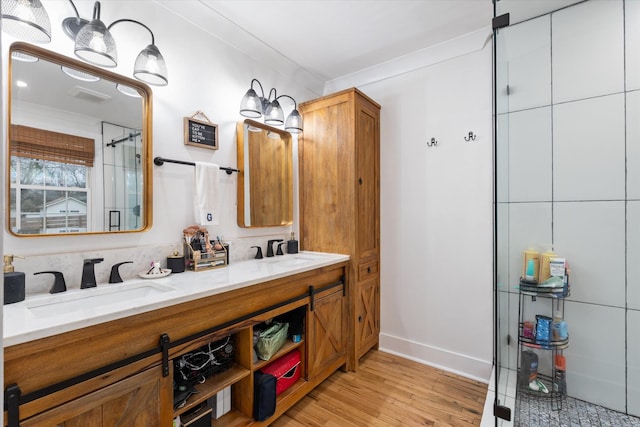 bathroom with a shower with door, wood-type flooring, ornamental molding, and vanity