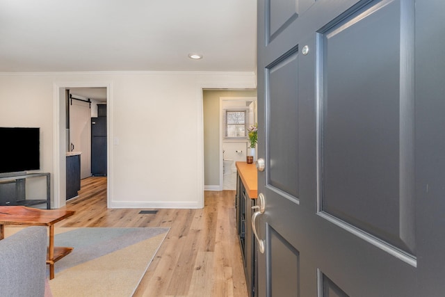 foyer featuring ornamental molding, a barn door, and light wood-type flooring