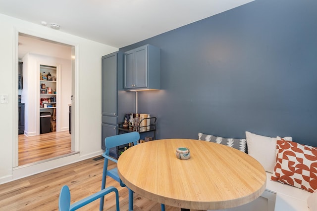 dining room with light hardwood / wood-style floors and built in shelves