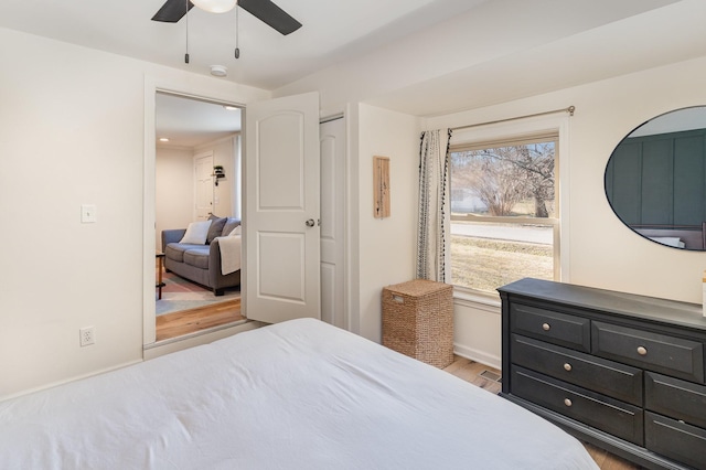 bedroom with multiple windows, light hardwood / wood-style flooring, ceiling fan, and a closet