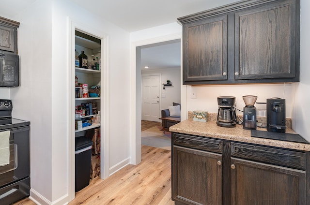 kitchen with light hardwood / wood-style flooring, dark brown cabinetry, and black appliances