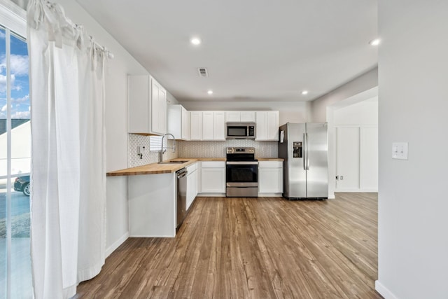 kitchen featuring white cabinetry, butcher block counters, sink, stainless steel appliances, and light hardwood / wood-style flooring