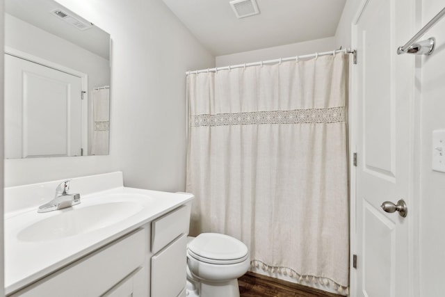 bathroom with walk in shower, vanity, and toilet