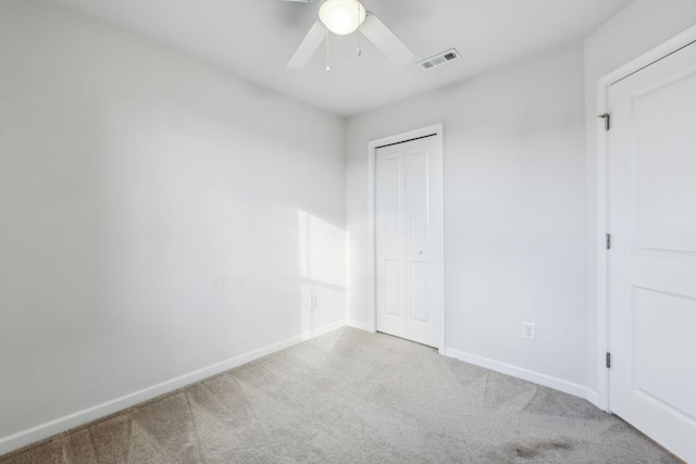 unfurnished bedroom featuring light colored carpet, a closet, and ceiling fan