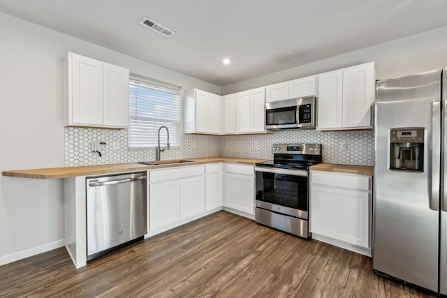 kitchen with stainless steel appliances, butcher block counters, sink, and white cabinets