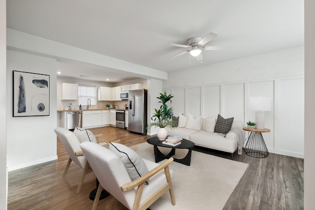 living room featuring ceiling fan, sink, and hardwood / wood-style floors