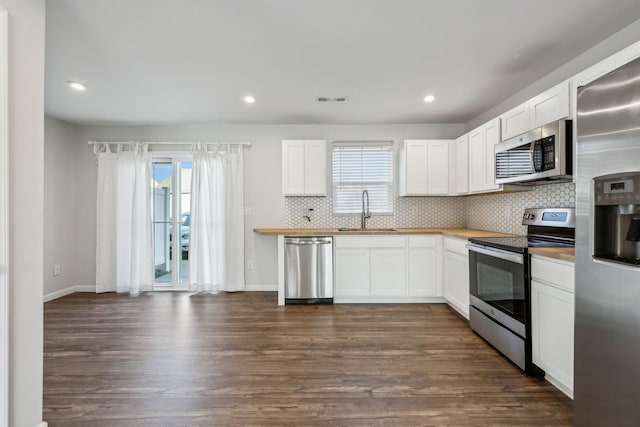 kitchen with sink, backsplash, stainless steel appliances, and white cabinets